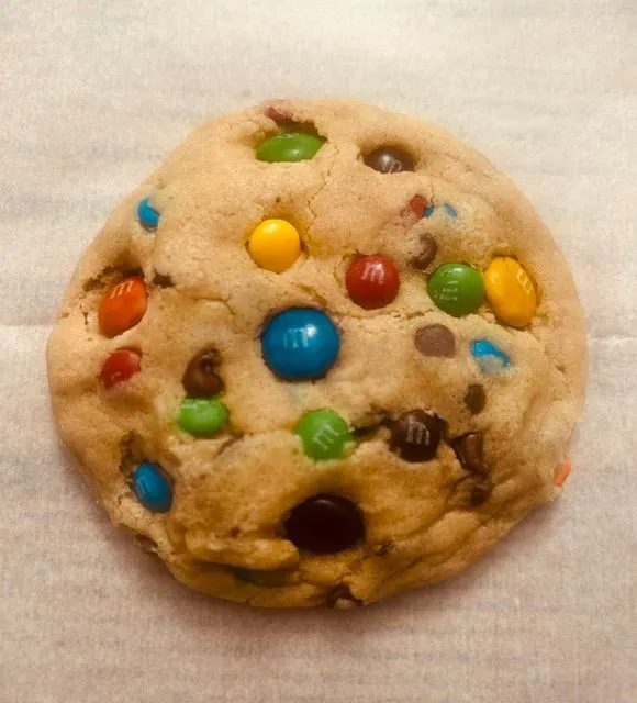 An M&M Overload Cookie from Sweet Home Cookie Mama, LLC with M&M candies and chocolate chips on top